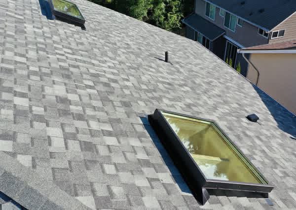Close-up aerial view of CertainTeed NorthGate Granite Gray shingles with two CrystaLite skylights, vents, and pipe penetrations in Sammamish, WA