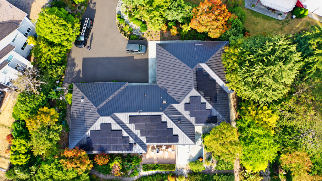 Solar panels and tall evergreens at a West Seattle, WA Nu-Ray standing seam metal roof project