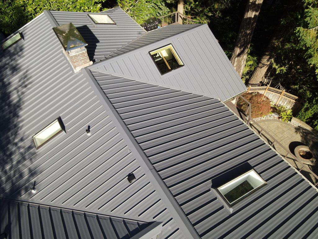 Drone aerial view of the completed Nu-Ray NRM-2000 standing seam metal roof complex with multiple skylights and chimney, Wilburton, Bellevue WA