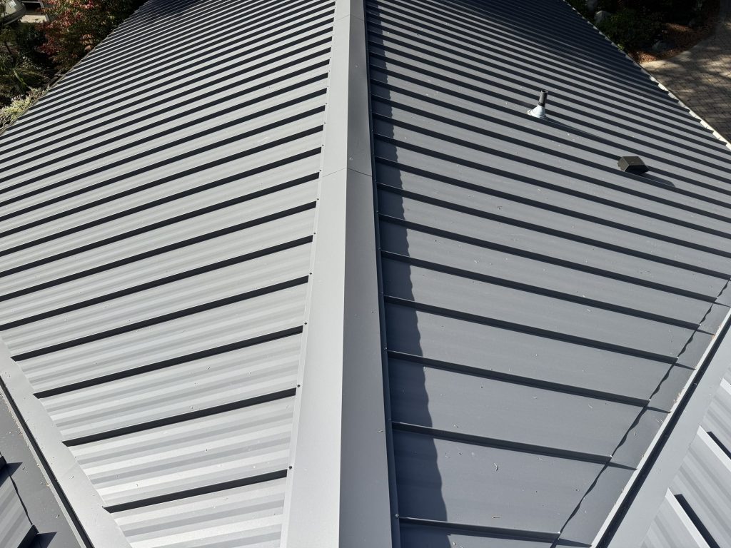 Ridge cap close-up showing crisp standing seams on a Charcoal Gray Nu-Ray NRM-2000 metal roof in Wilburton, Bellevue WA